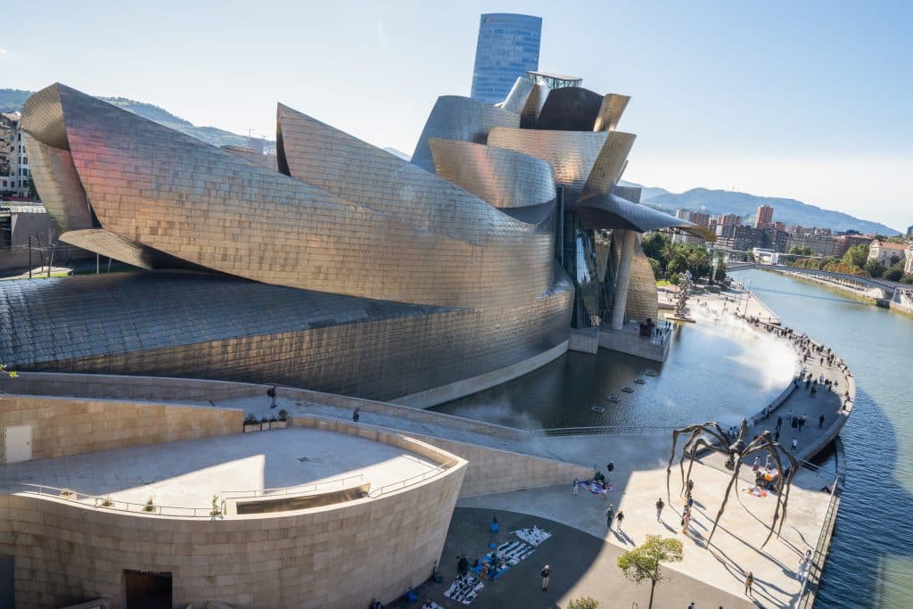 The Guggenheim Museum of Bilbao, its exterior all swooping, sharp pieces of metal jutting out at different angles.
