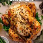 Whole roasted chicken seasoned with herbs on a serving plate, surrounded by fresh parsley and green beans, with text overlay about making herb roasted chicken.