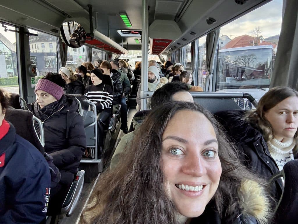 Kate taking a selfie while riding a bus. Two French women give her the side-eye.