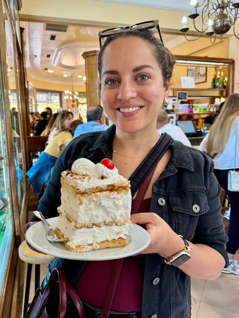 Kate holding a large, tall cake with layers of meringue.
