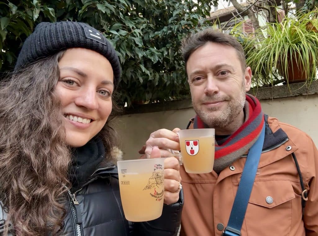 Kate and Charlie smiling and holding hot apple juice in mugs.