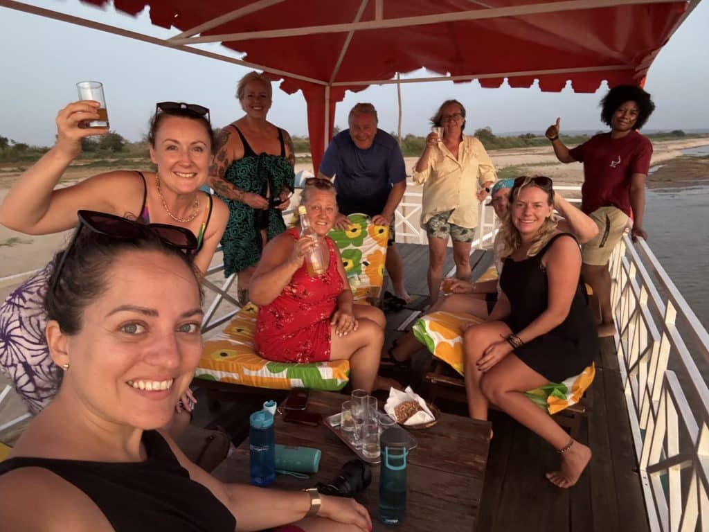 Kate and a big group of friends sitting on the top level of a boat moored on the side of the river in Madagascar.