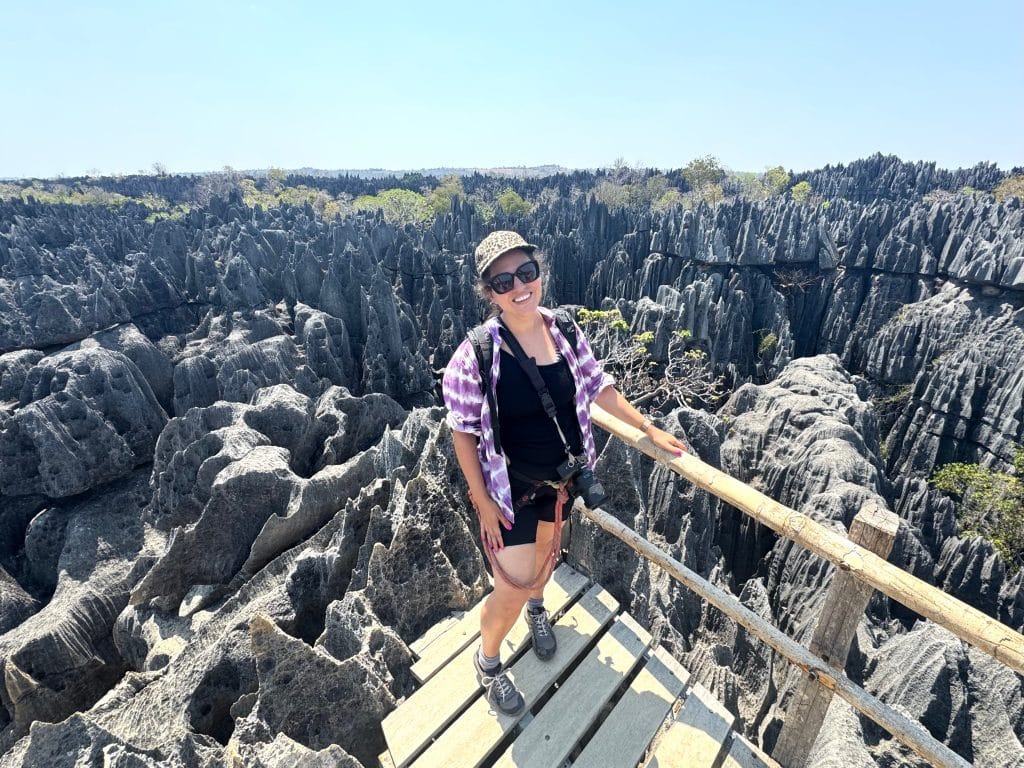 Kate standing on a wooden platform surrounded by tall, jagged, gray rocks in every direction.
