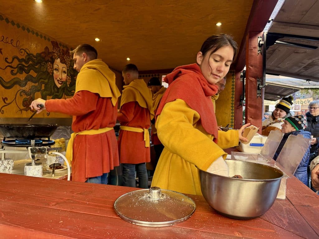 Food service workers wearing red and yellow medieval tops as they serve food.