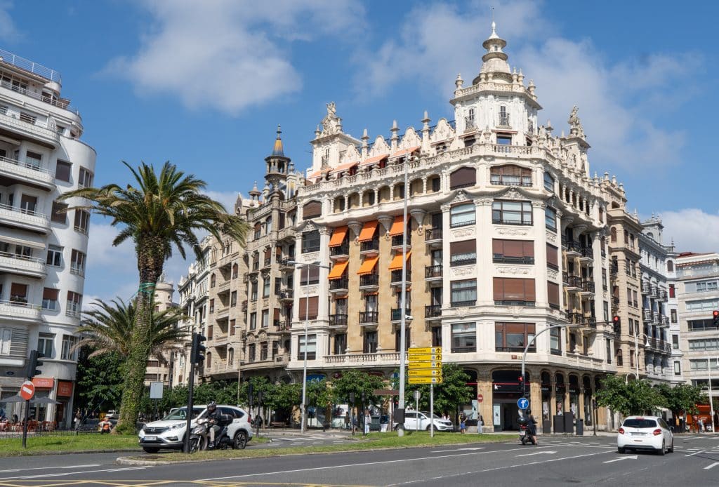A tall, crenellated building on a busy street in San Sebastián.