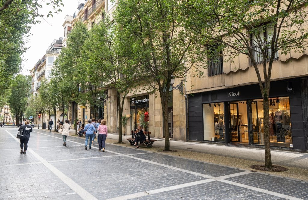 A wide, pedestrianized shopping street in San Sebastián on a cloudy day.