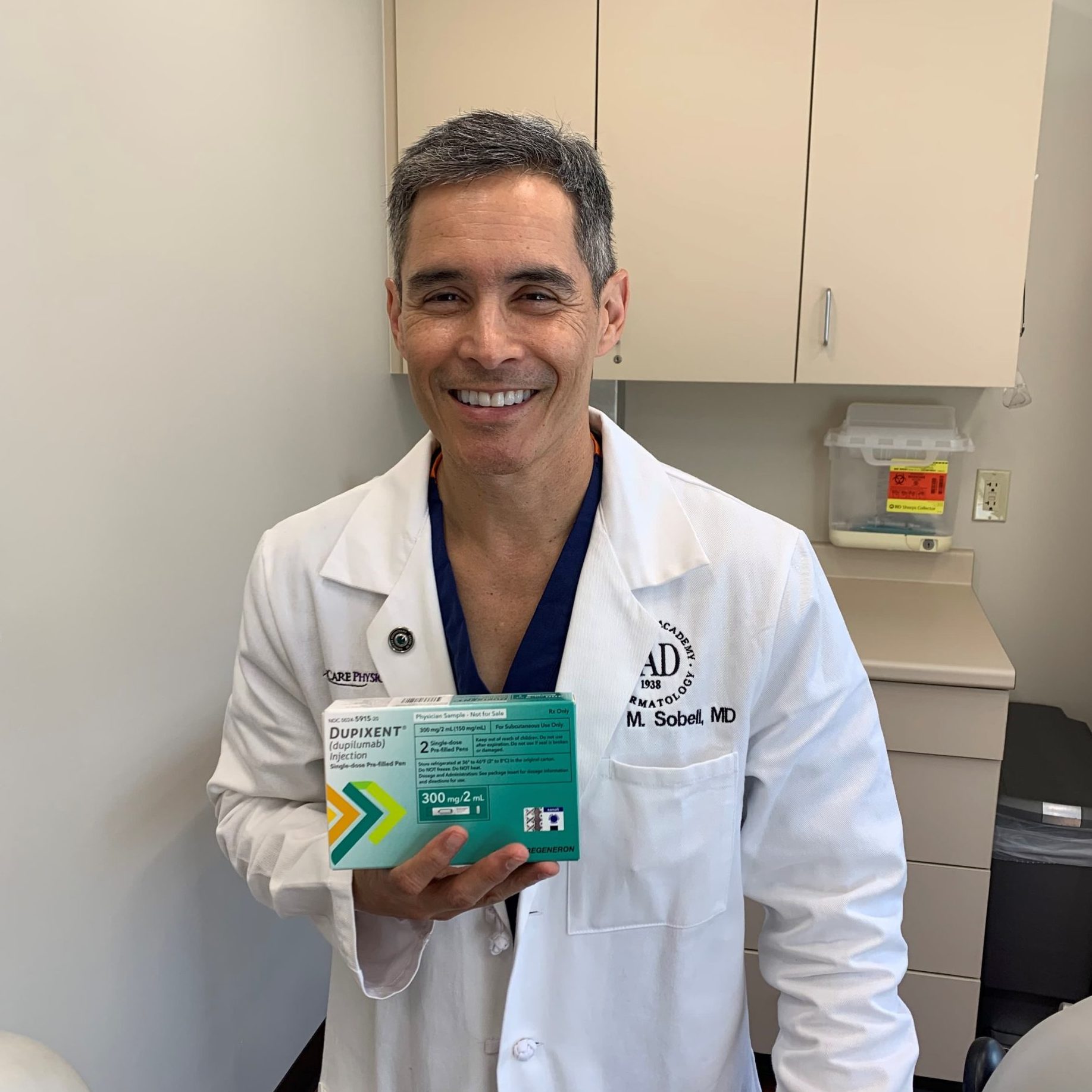 Dr. Sobell holding a box of Dupixent FDA approved for chronic hives.