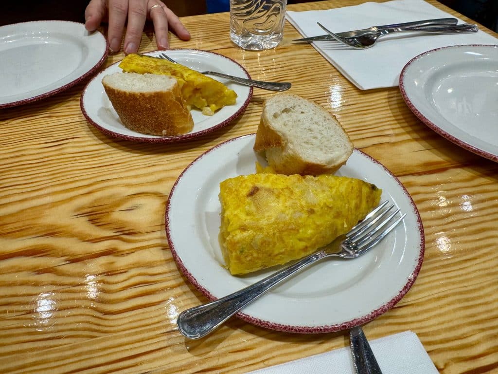 Two big triangular slices of Spanish tortilla on a plate with bread.