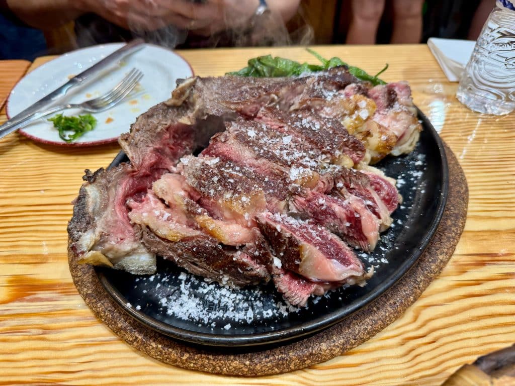 A sizzling plate of sliced steak, very red and fatty.