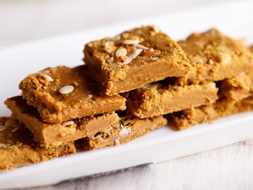 besan barfi stacked on white tray,