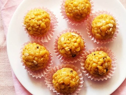 closeup shot of six boondi ladoo in pink muffin liners on a white plate