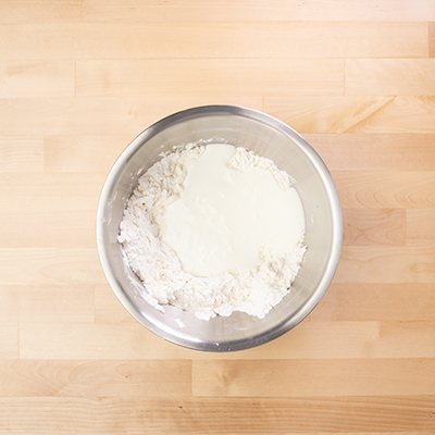 Bowl of dry ingredients and butter with unmixed buttermilk on top.