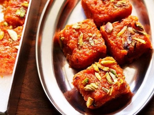 carrot barfi squares on an oval steel plate.