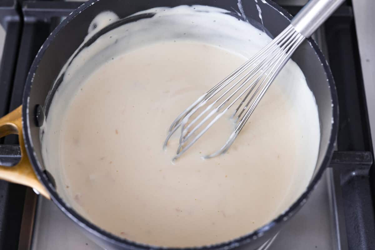 Gravy ingredients added to a sauce pan being whisked together. 