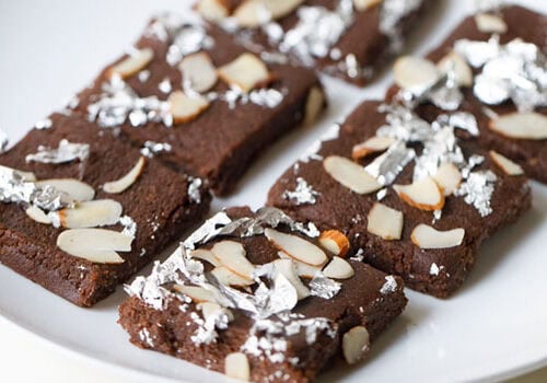 Closeup shot of chocolate barfi with almonds and silver foil.
