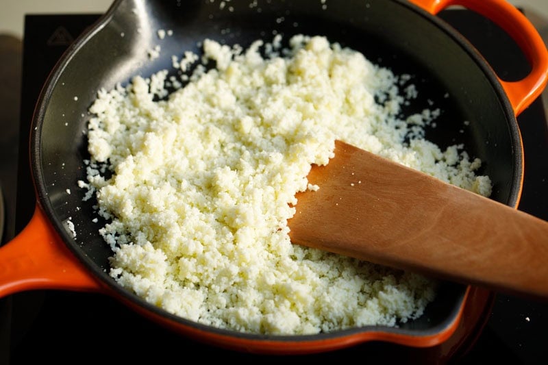 Grated mawa being cooked in skillet.