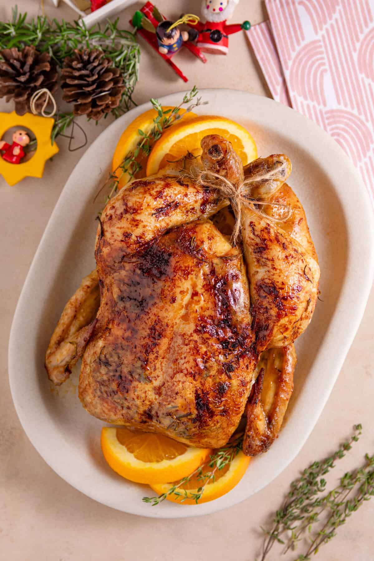 Process shot for a Christmas roast chicken recipe showing the finished roast chicken on a serving dish.