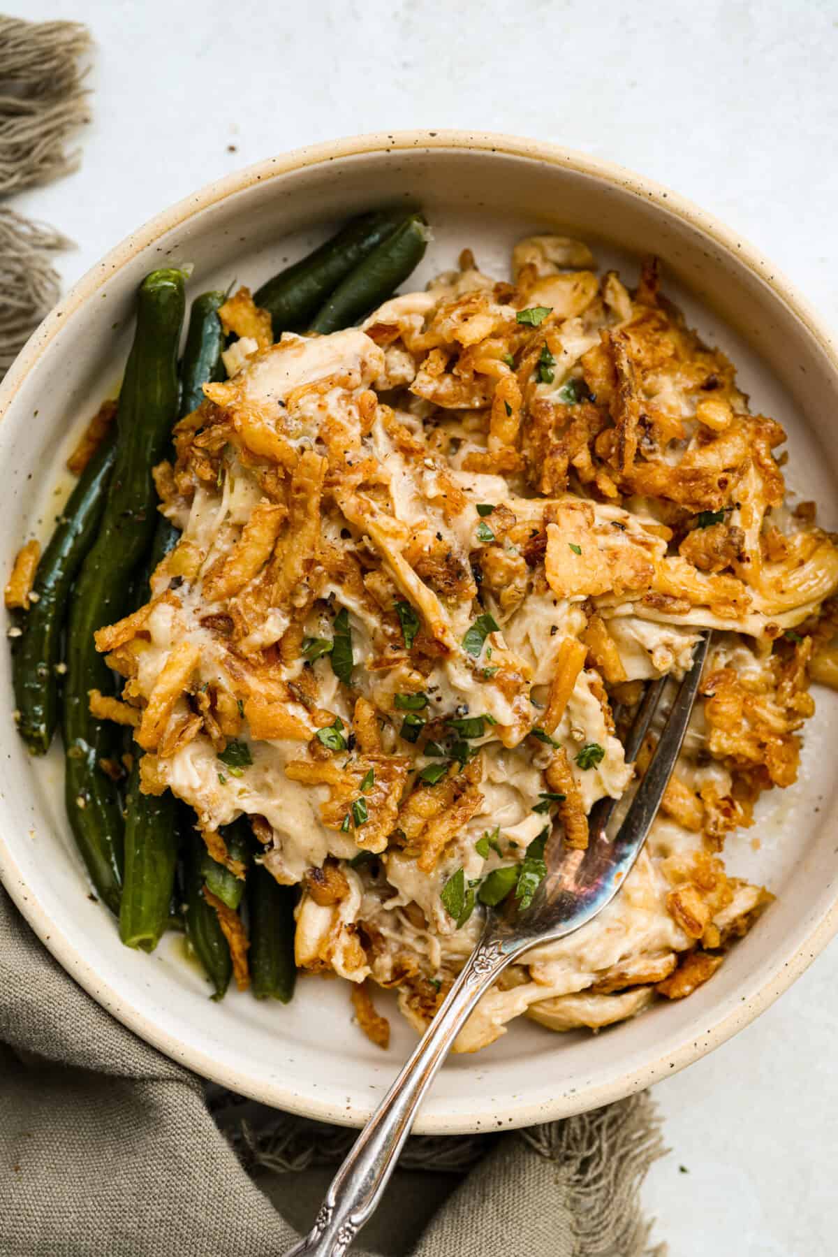 Creamy, cheesy, and packed with shredded chicken, this French onion chicken casserole is comfort food at its best! Inspired by French onion soup and dip, it’s topped with crispy fried onions for a crunchy finish. Plated French onion chicken casserole with a side of green beans.