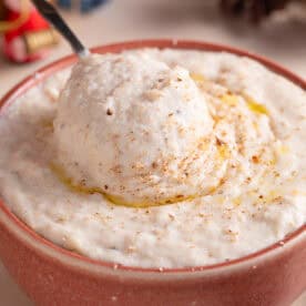 A bowl of gluten free bead sauce with a spoon dunked in, and festive decorations behind.