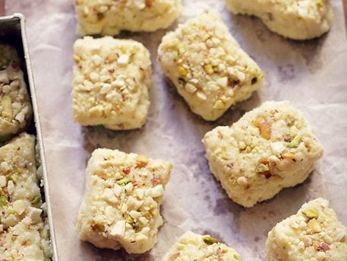 squares of kalakand laid out on a piece of parchment for serving