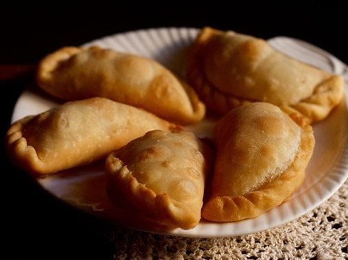 closeup photo of five karanji pieces on a white plate