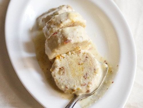 kulfi slices on white oval plate with spoon.