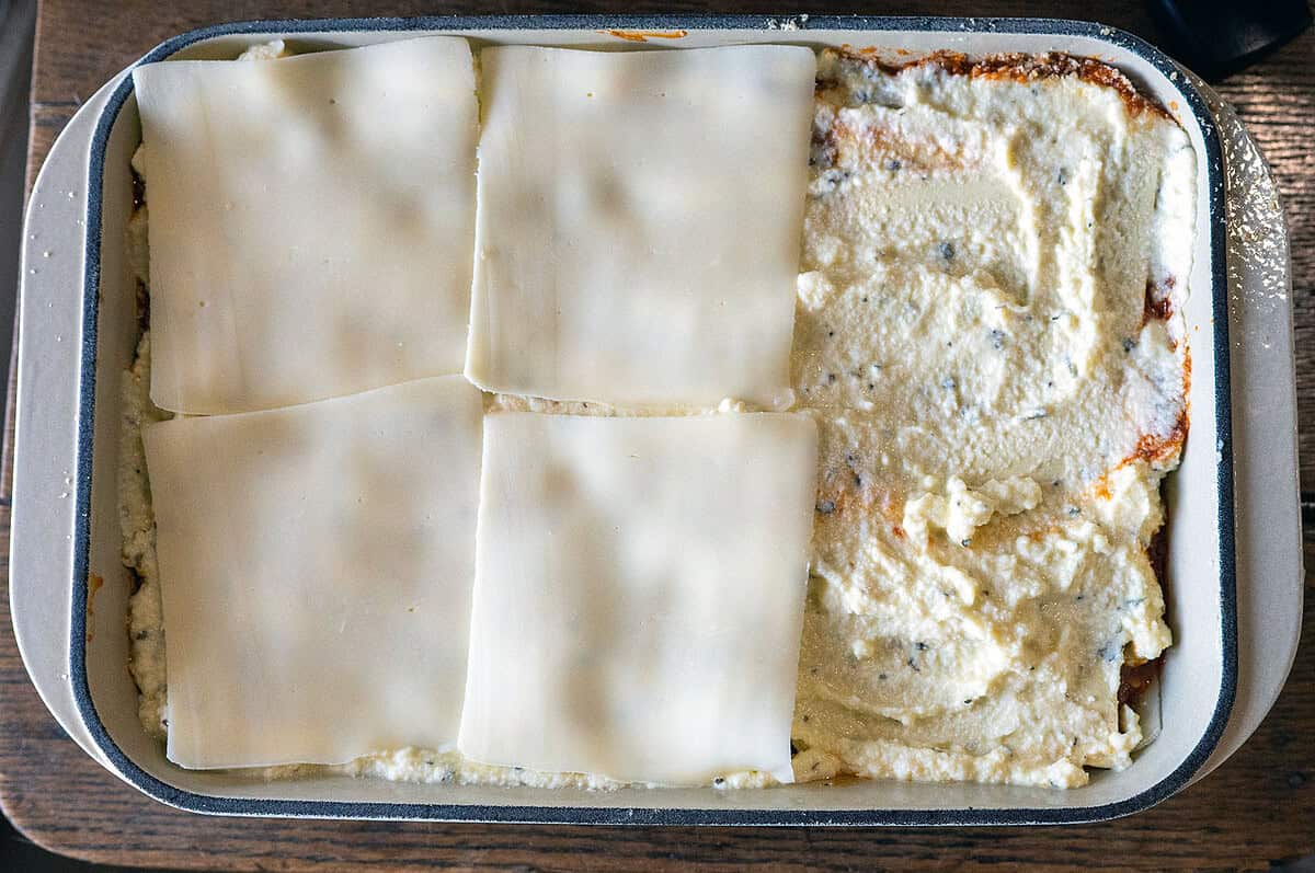 step-by-step lasagna layers: sauce, noodles, ricotta, mozzarella