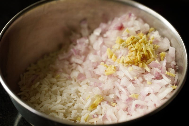 Chopped onions and ginger in bowl with poha.