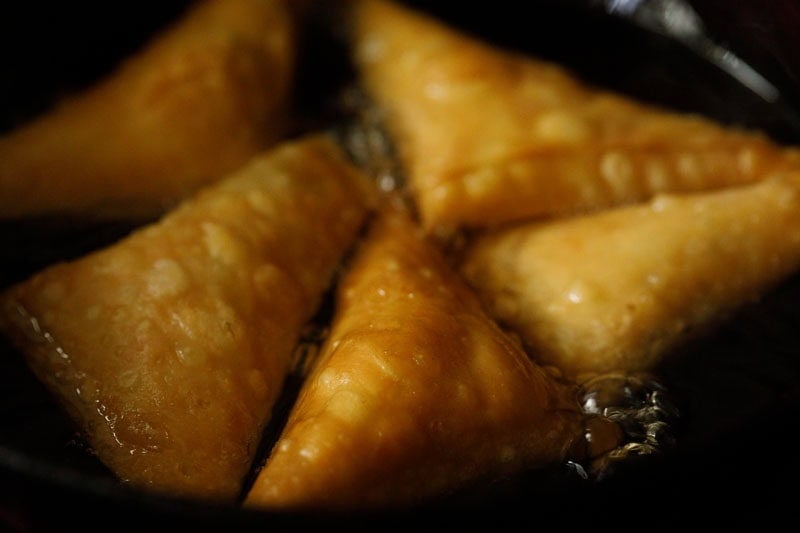 Golden fried patti samosa in oil in kadai.