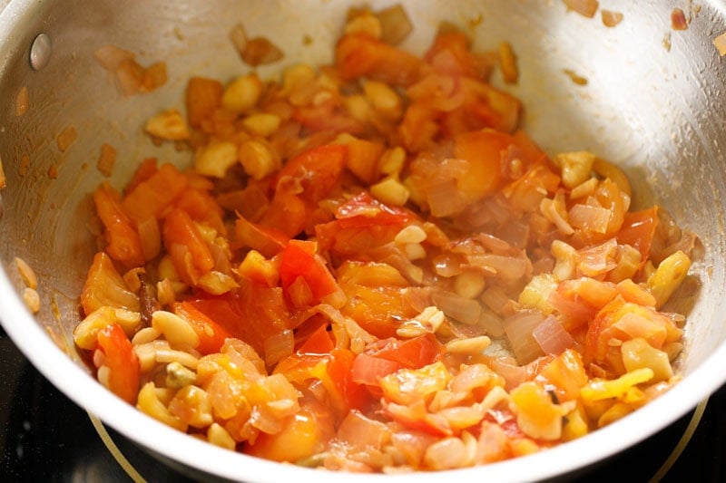 Tomatoes getting sautéed in skillet.