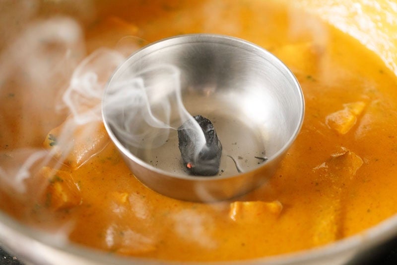 Small steel bowl with charcoal inside kept on the gravy and smoke coming out from the charcoal.