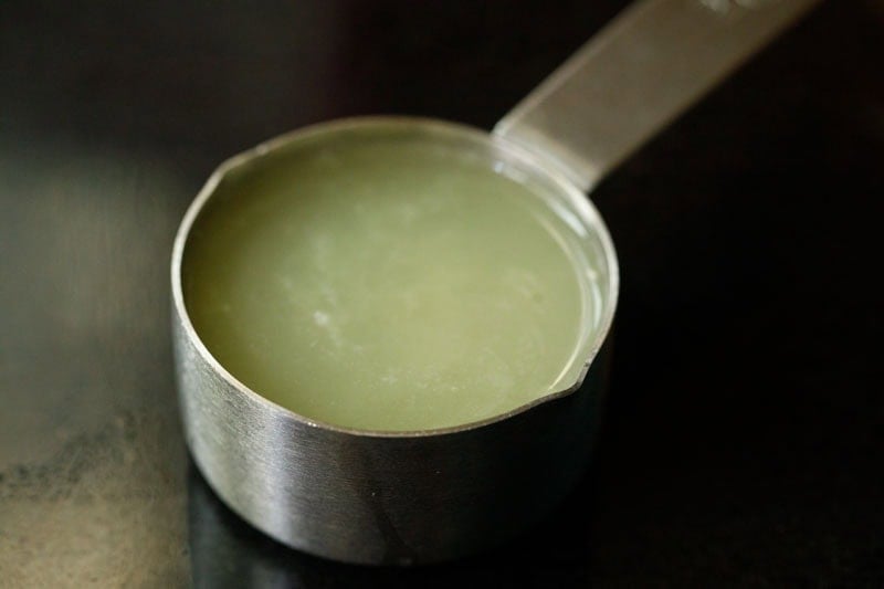 Metal measuring cup with lemon juice.