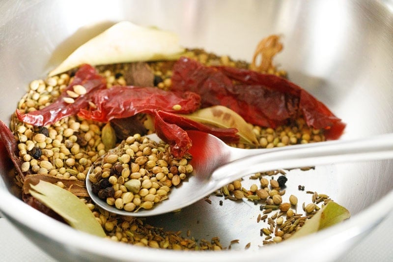 Spices in kadai or pan being roasted with a spoon.