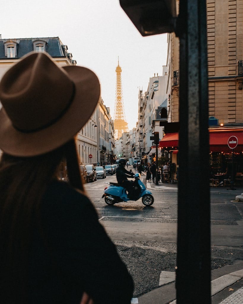 View of Eiffel Tower from a Paris street with a scooter and pedestrian.