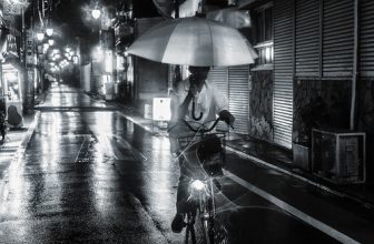 A cyclist holding an umbrella