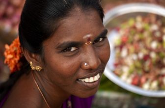 Woman With Bindi, Nose Piercing And Tied Hair With Flowers Smiling At The Camera, Madurai, India