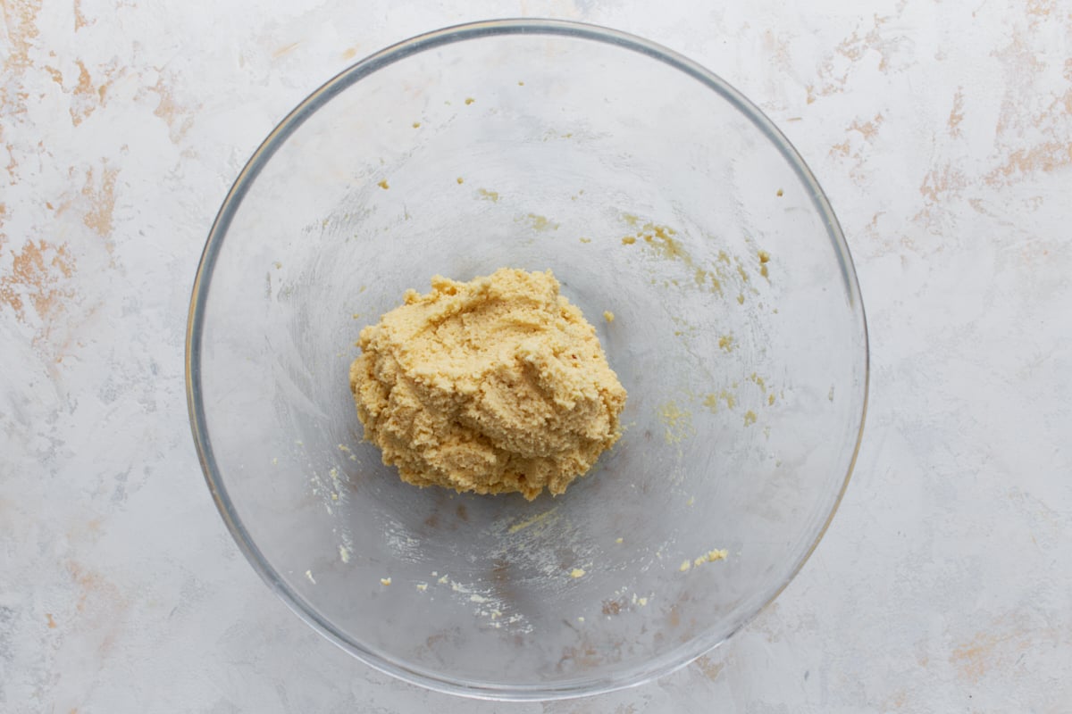 Almond flour sugar cookie dough combined and formed into a soft ball in a glass bowl.