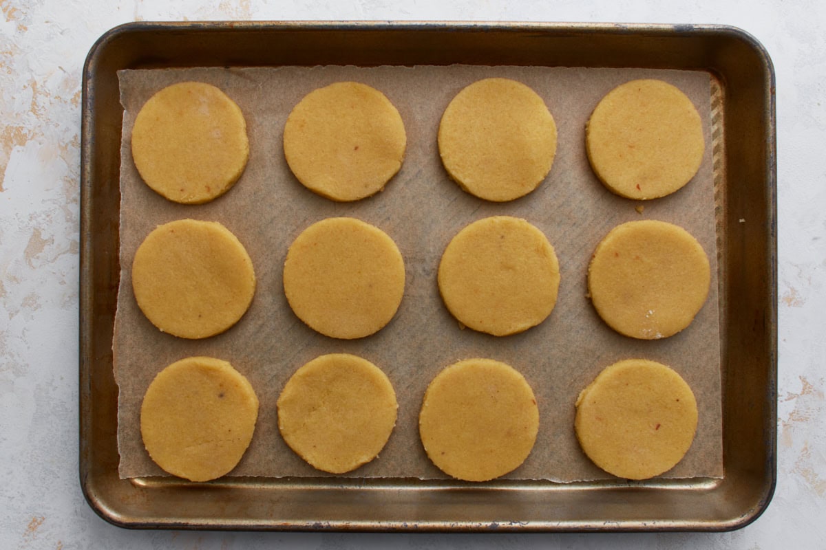 Unbaked almond flour sugar cookies arranged evenly on a parchment-lined baking sheet.