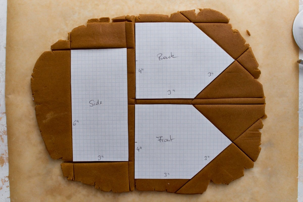 Rolled dough with graph-paper templates labeled front, back, and side, showing measurements for cutting each house piece before baking.