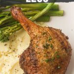A cooked duck leg served on mashed potatoes with asparagus and broccolini, shown under text about making air fried duck legs and a website for the full recipe.