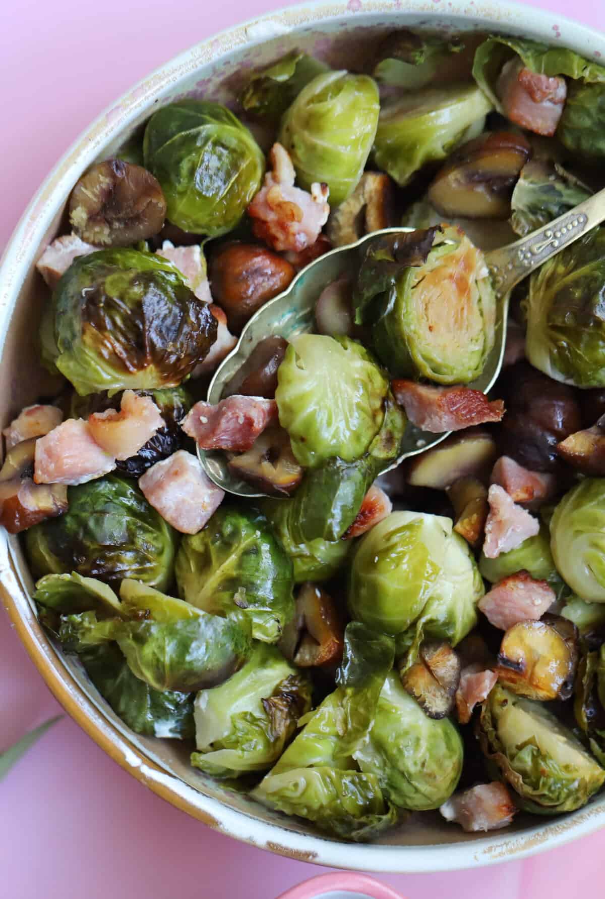A bowl of brussels sprouts with chestnuts and bacon.