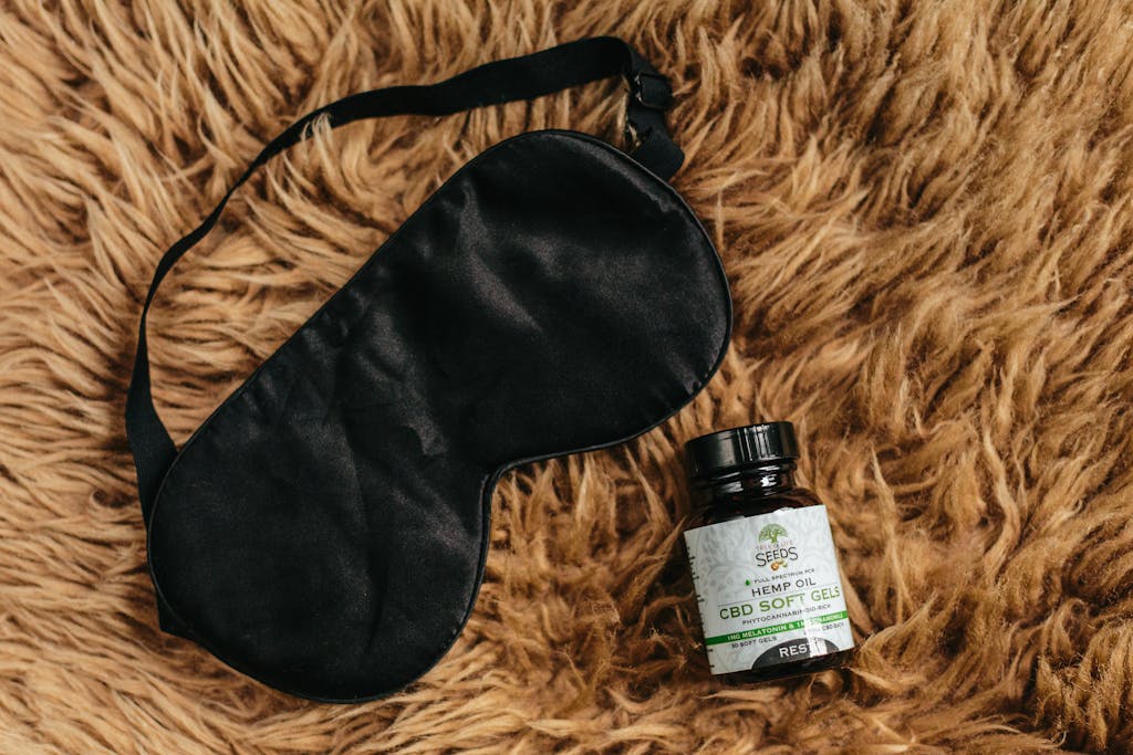 CBD soft gels and black eye mask laid on brown fur promoting relaxation and sleep, are medical supplies to pack for solo trips