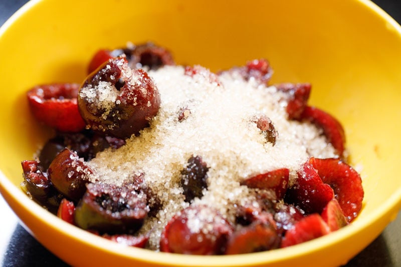 Cherries with sugar in yellow bowl.