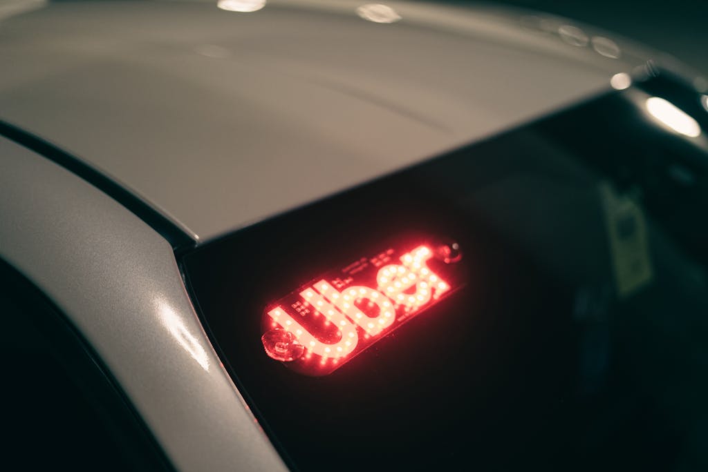 Close-up of a ride-sharing car with a bright red illuminated sign for night-time travel contacted through apps for solo travellers