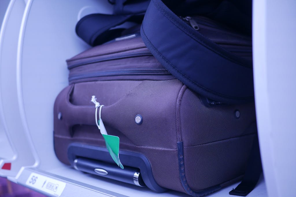 Close-up of luggage in an airplane's overhead compartment, showcasing travel essentials and how to pack light