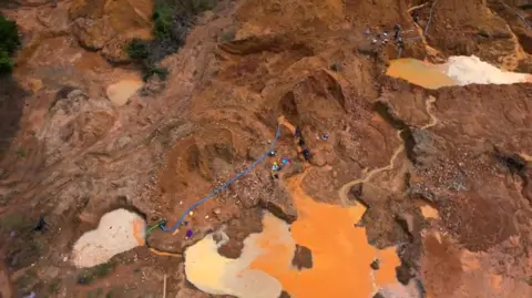 David Wilkins / BBC An aerial shot of a mining site - pools of dirty water can be seen amid the dug up earth.