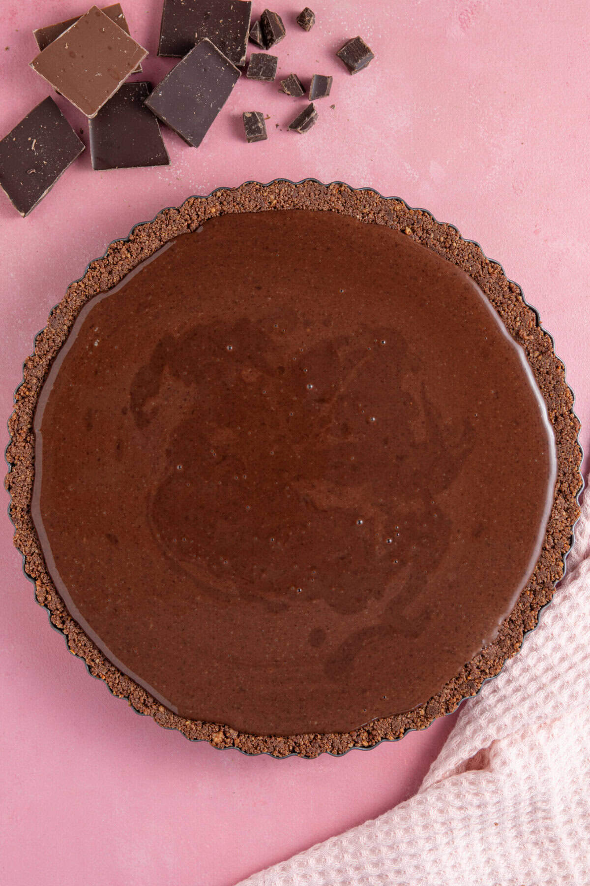 A process shot for a gluten free chocolate tart showing the ganache filling poured into the base.