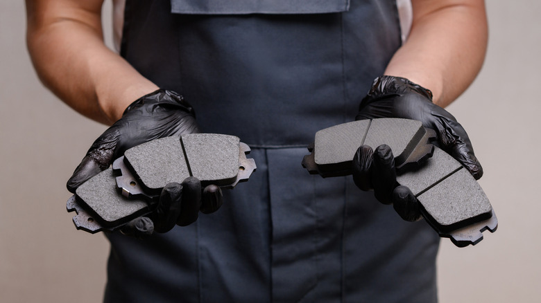 A mechanic holding four new brake pads