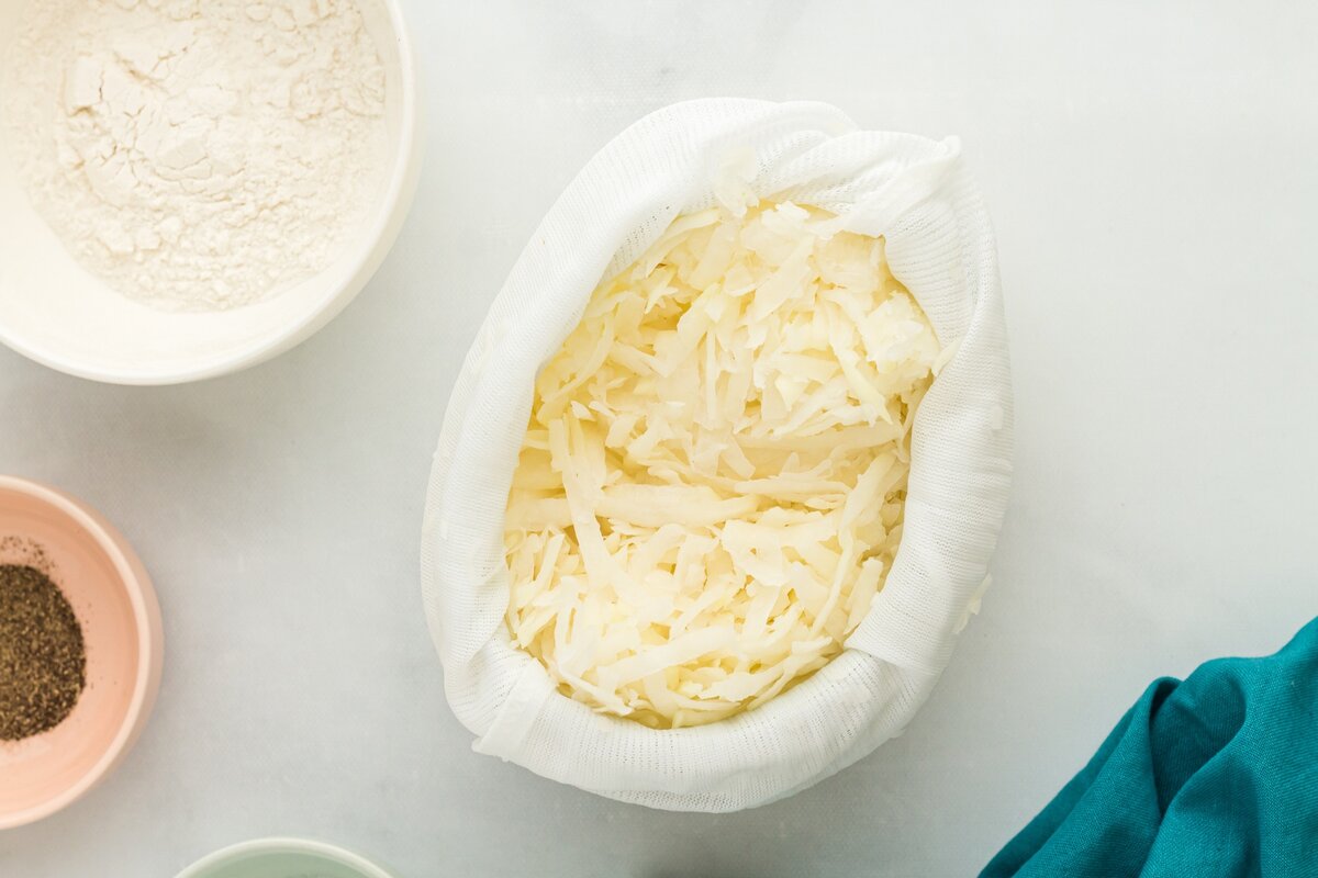 Grated potatoes wrapped in cheesecloth, ready to be squeezed to remove moisture.