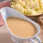 A jug of miso gravy with a bowl of mashed potato behind.